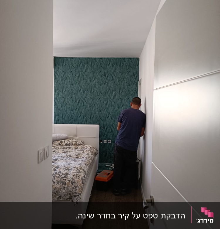 אדם עובד ליד קיר עם טפט ירוק